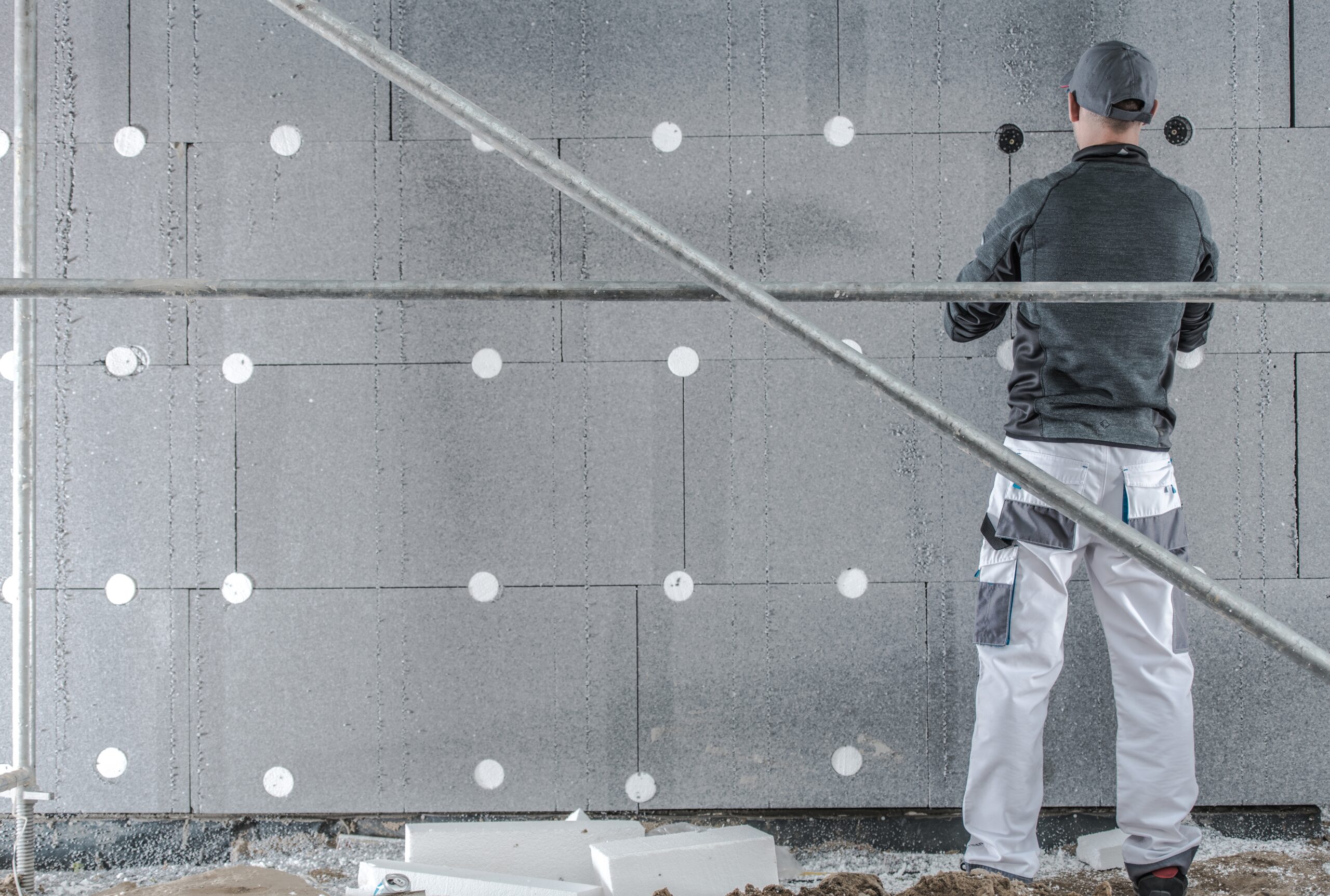 Caucasian Construction Worker Installing Molded Graphite Polystyrene. House Insulation.